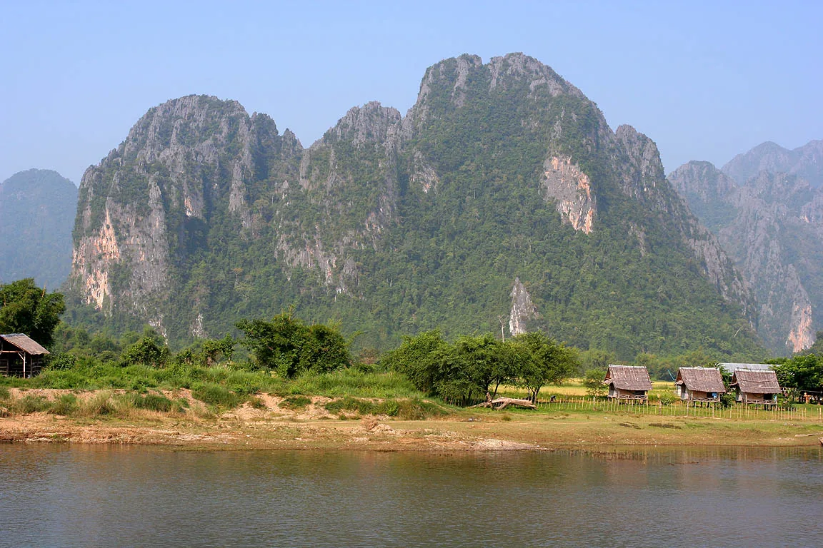 Karst mountains rising over the Nam Song River and riverside huts at Vang Vieng