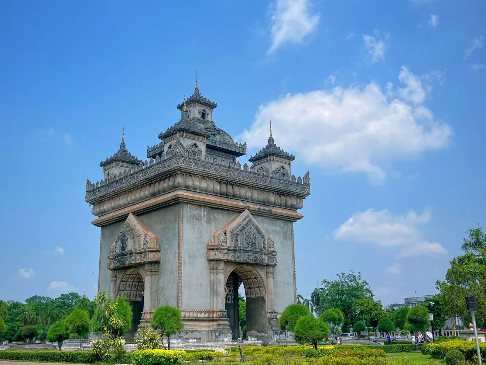 Full view of Patuxai monument and its gardens beneath a blue sky in Vientiane