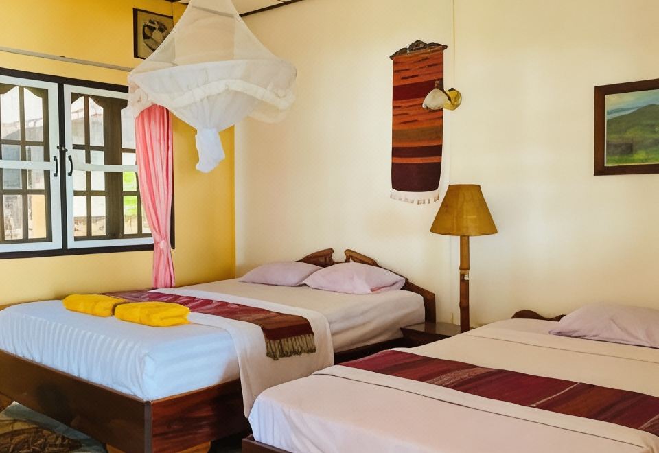 A twin room with mosquito nets over both beds and a woven hanging on the wall