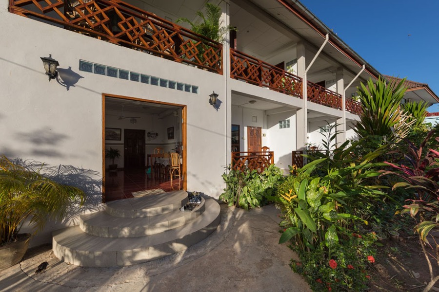 The two-storey guesthouse seen from a garden path, with stone steps and a wooden lattice balcony above
