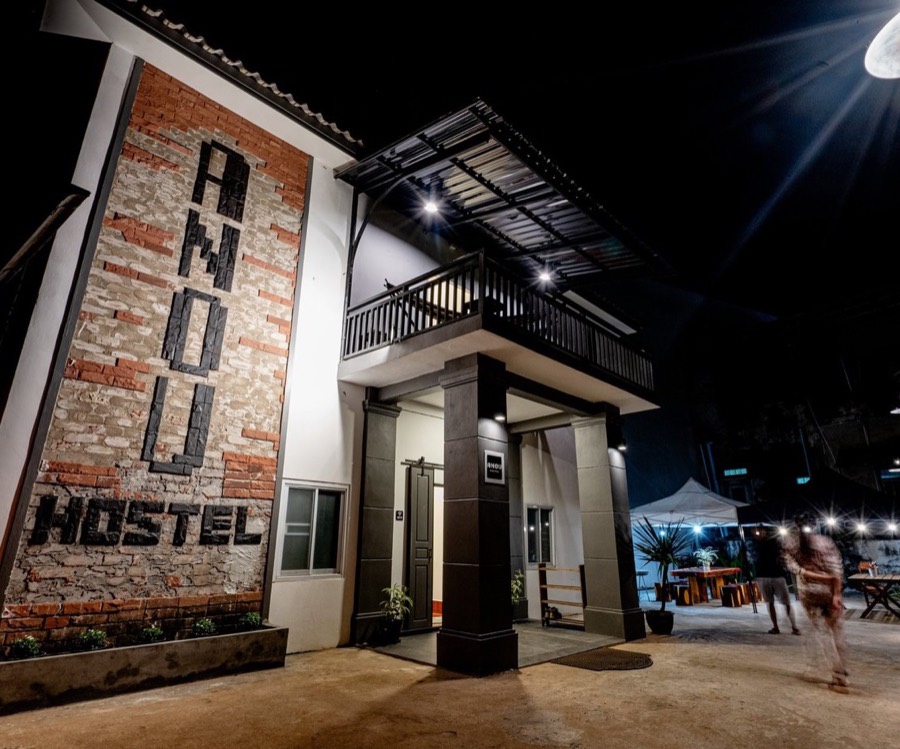 The hostel entrance at night, its name in dark lettering on an exposed brick facade