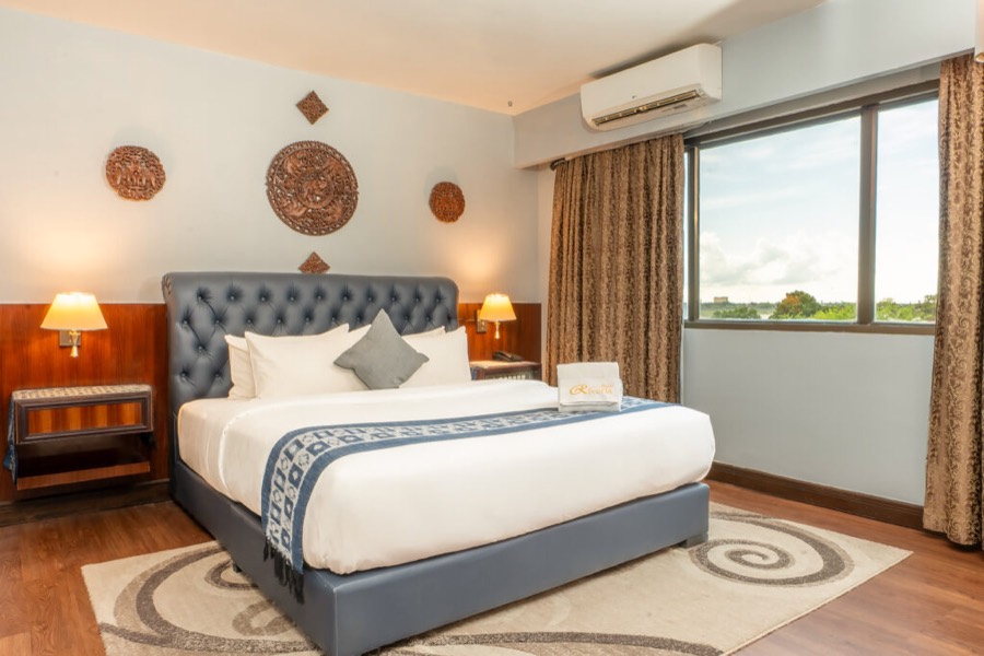 A room with a king bed, wood panelling and a window looking over the river