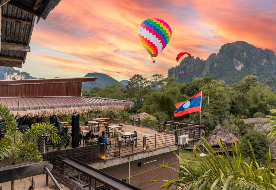 A rooftop terrace at sunset, with hot-air balloons over the karst hills beyond