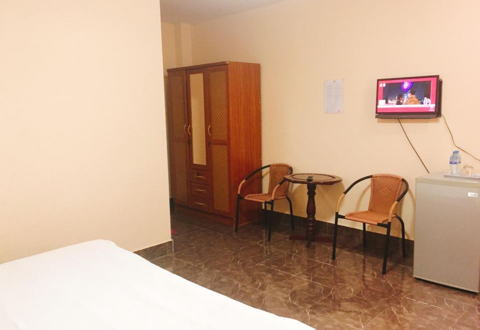 A private room with a wardrobe, table and chairs and a wall-mounted television