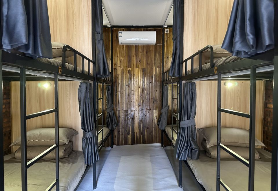 A dormitory of wooden bunks, each with its own curtain and reading light